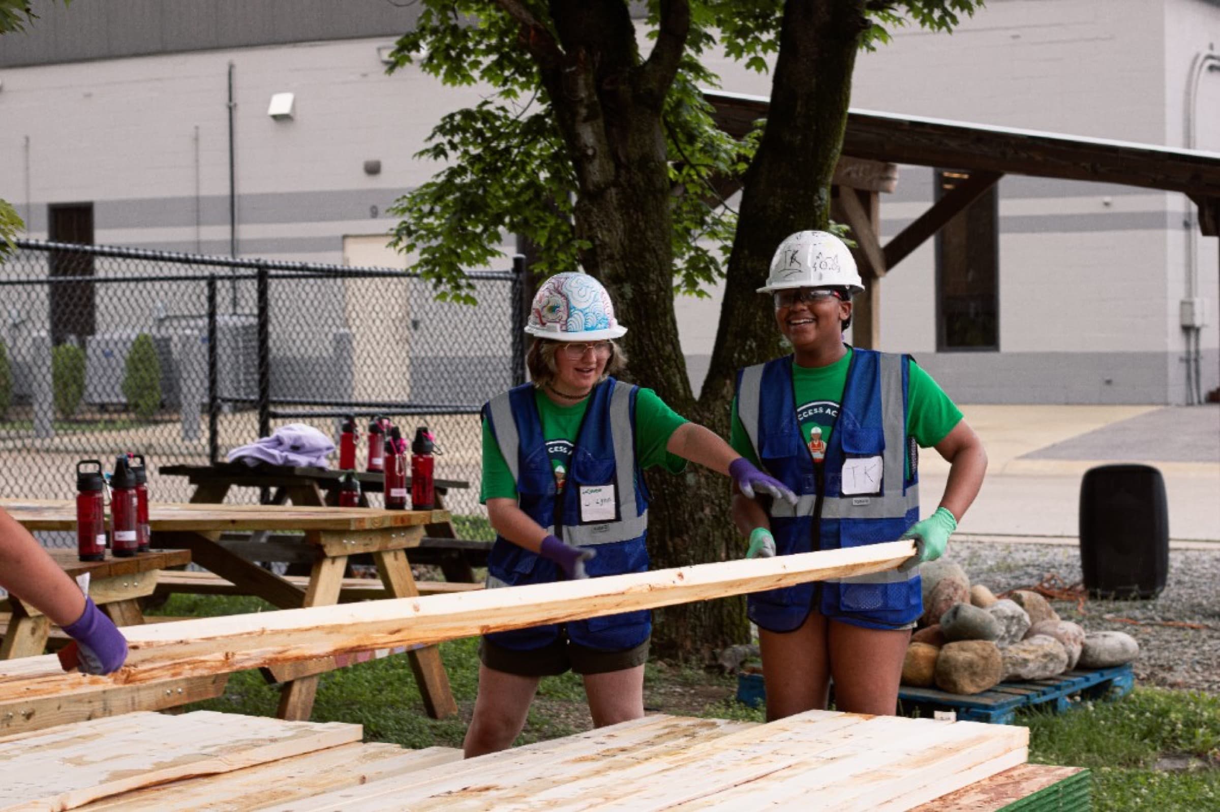 Students using tools in pink hard hats