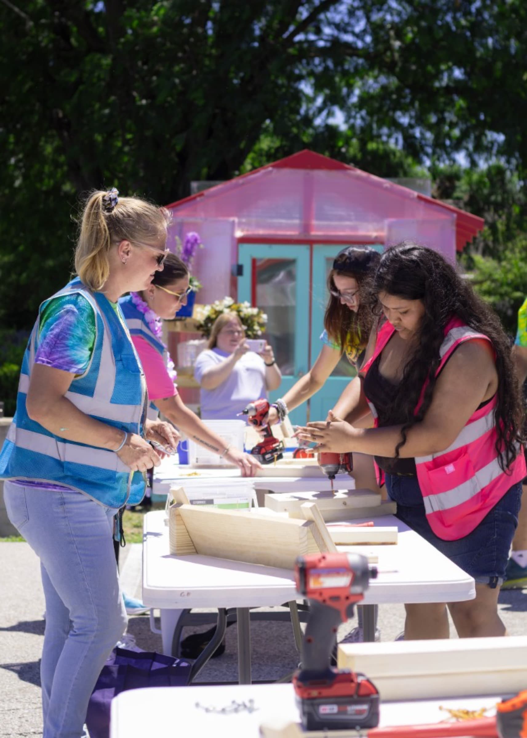 Students using tools in pink hard hats