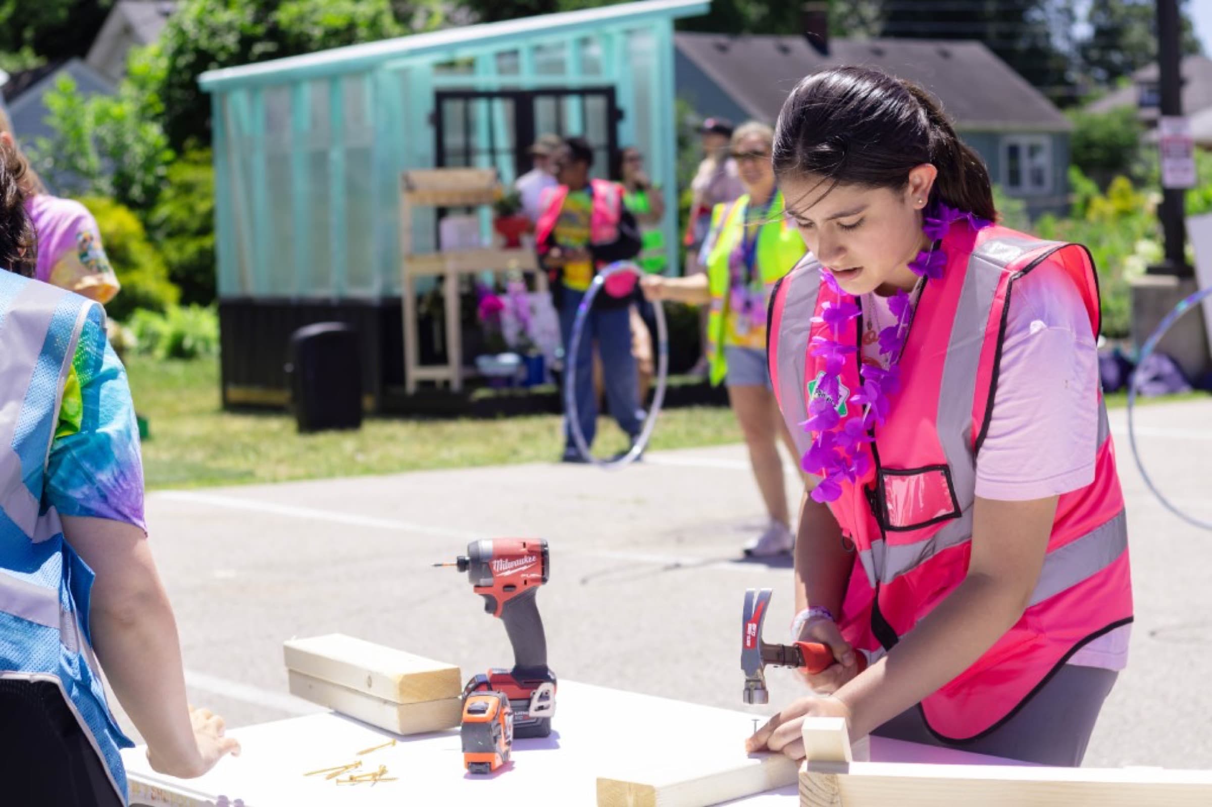 Students using tools in pink hard hats