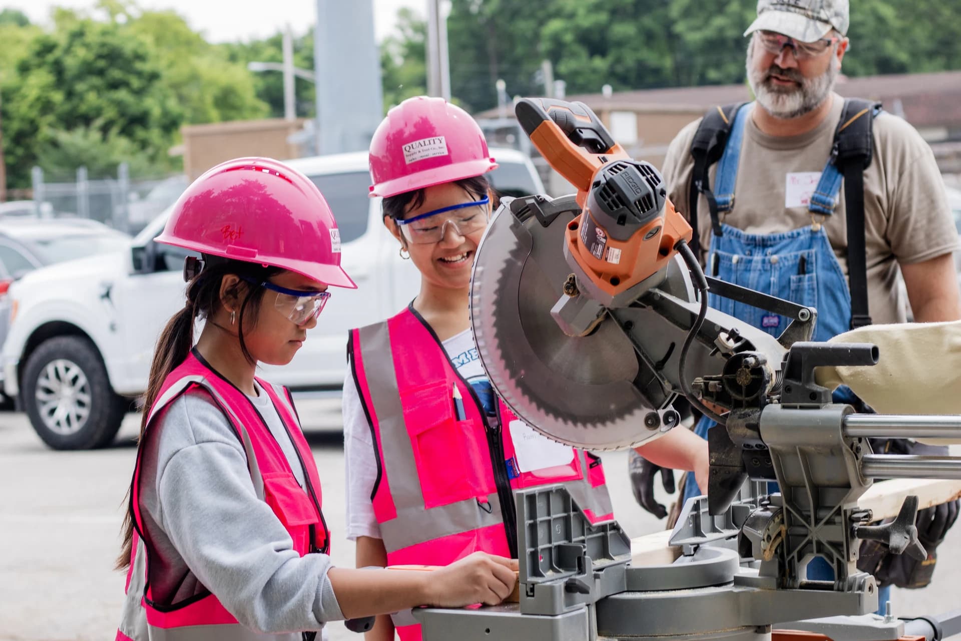Students using tools in pink hard hats