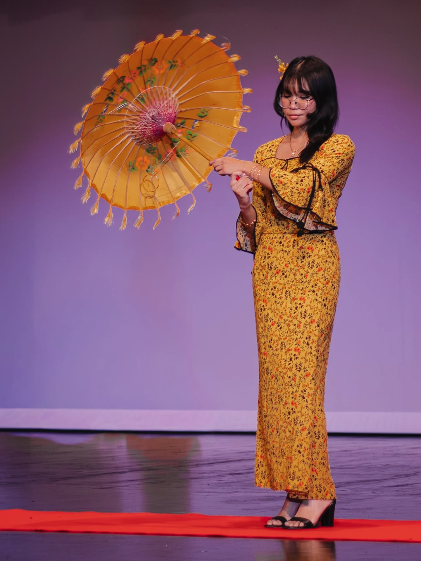 Student performer holding a parasol on stage
