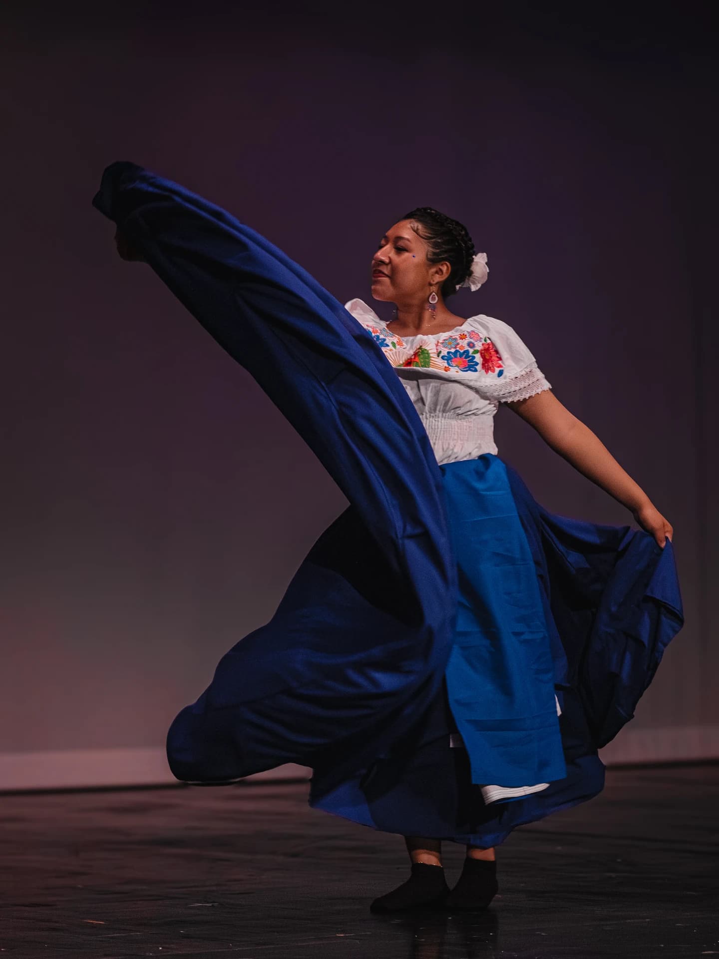 Student performer in a spinning skirt on stage