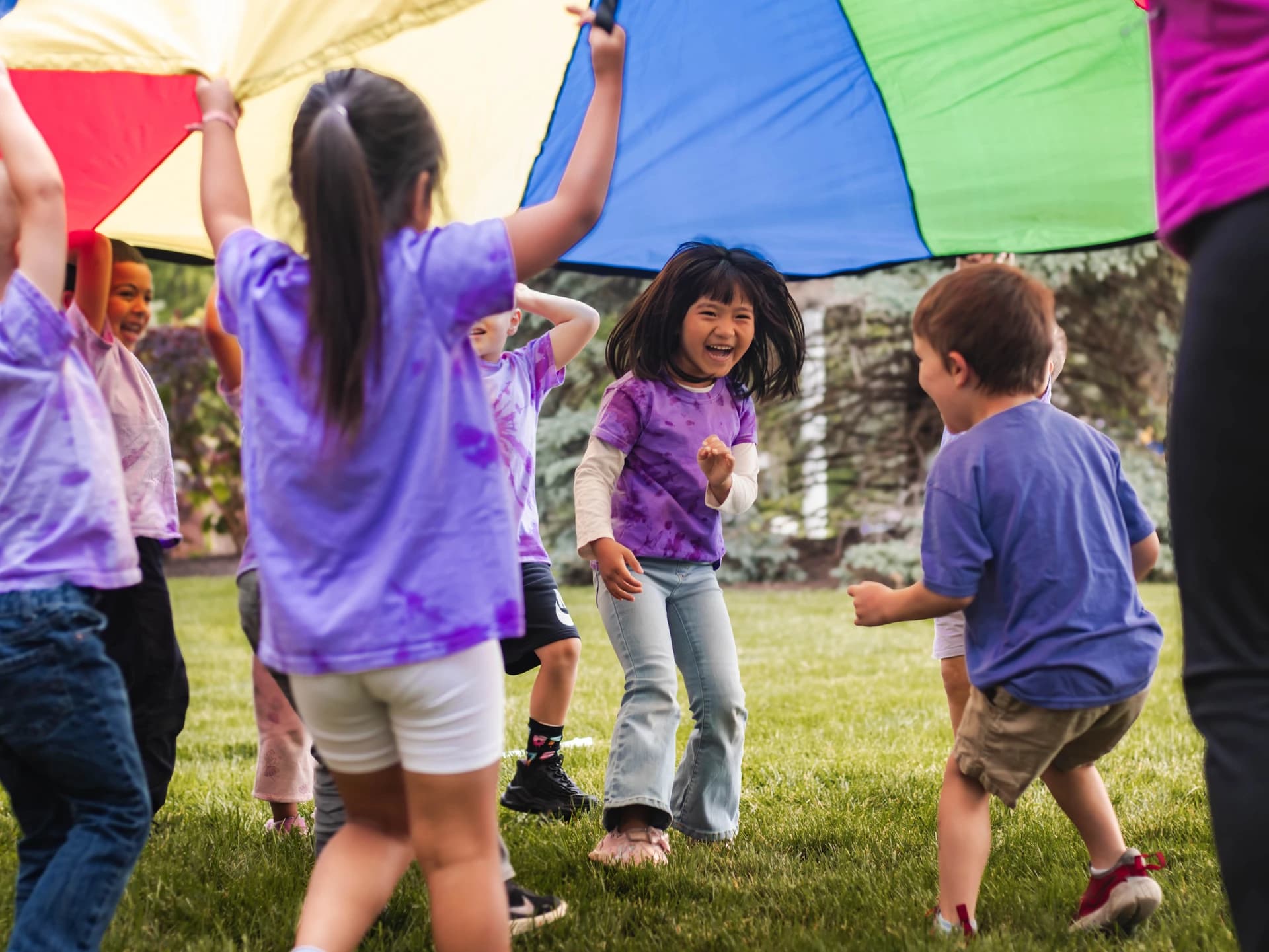 Children running under a colorful parachute